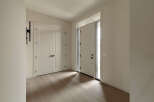Step into a bright and airy entryway featuring a modern black wall sconce and elegant double doors.