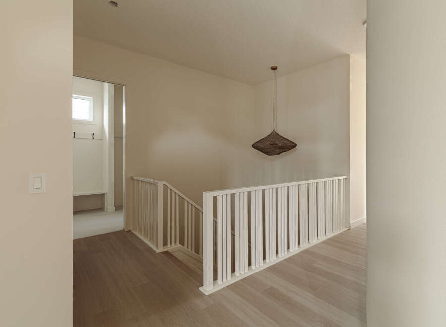 Step into a beautifully designed hallway featuring a modern staircase with white railings and light wood flooring.