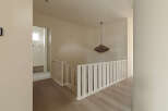 Step into a beautifully designed hallway featuring a modern staircase with white railings and light wood flooring.