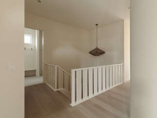 Step into a beautifully designed hallway featuring a modern staircase with white railings and light wood flooring.
