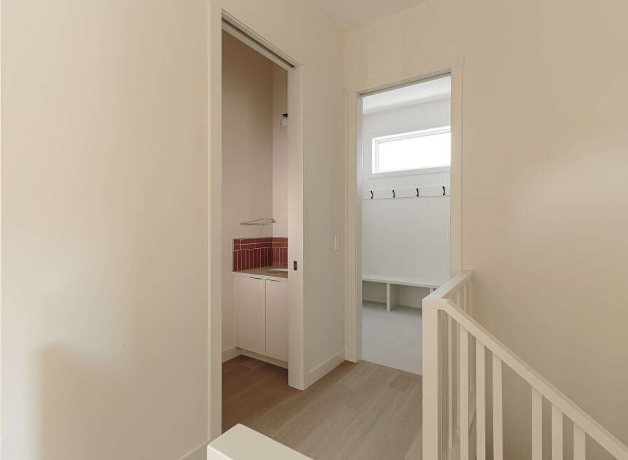 Discover modern living with this bright and airy hallway, featuring a convenient mudroom with ample storage and a sleek sink area.