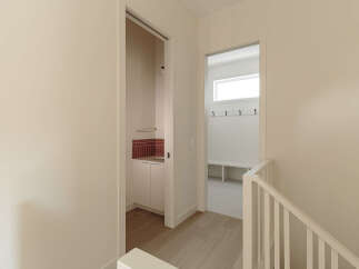 Discover modern living with this bright and airy hallway, featuring a convenient mudroom with ample storage and a sleek sink area.