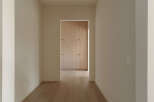 Step into this inviting hallway, featuring warm, light-toned hardwood floors that lead your eye towards a beautifully crafted built-in closet.
