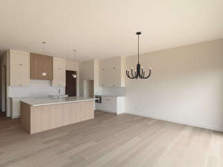 Experience modern living in this stunning kitchen and dining area, featuring sleek white cabinetry, a beautiful wood-accented island with a quartz countertop, and a striking black chandelier.