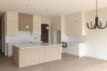 This modern kitchen boasts a sleek design with ample white cabinetry and a large island featuring a light wood finish.