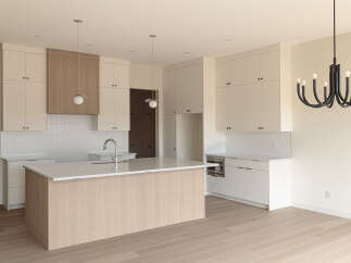 This modern kitchen boasts a sleek design with ample white cabinetry and a large island featuring a light wood finish.