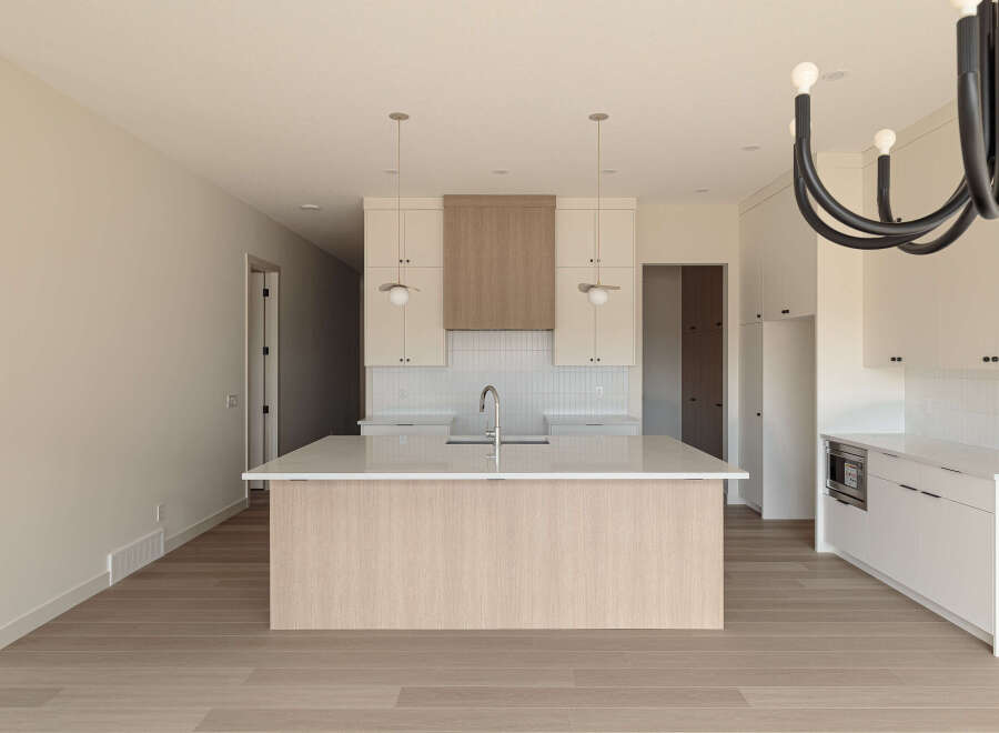 Experience modern living in this stunning kitchen featuring a large island with a waterfall countertop and a sleek faucet.