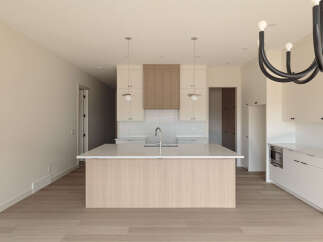 Experience modern living in this stunning kitchen featuring a large island with a waterfall countertop and a sleek faucet.