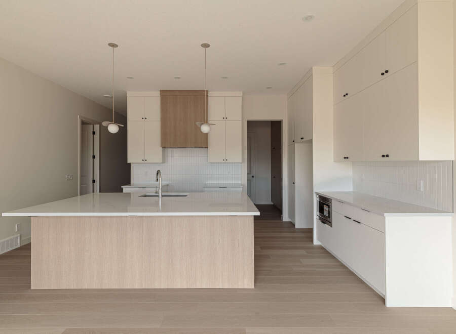 This modern kitchen boasts a spacious island with a waterfall countertop, perfect for meal prep and casual dining.