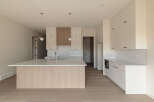 This modern kitchen boasts a spacious island with a waterfall countertop, perfect for meal prep and casual dining.