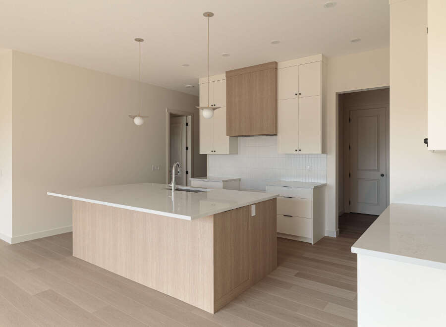 Discover this modern kitchen featuring a spacious island with a waterfall countertop and a sleek faucet.