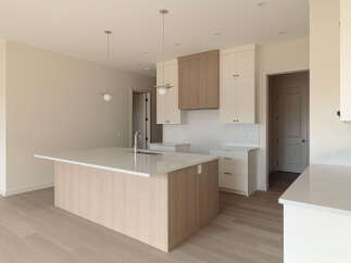 Discover this modern kitchen featuring a spacious island with a waterfall countertop and a sleek faucet.