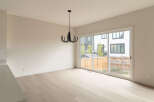 This modern dining area features a sleek black chandelier hanging above light wood flooring.