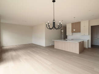 Experience modern living in this spacious open-concept home, featuring a sleek kitchen island and elegant cabinetry.