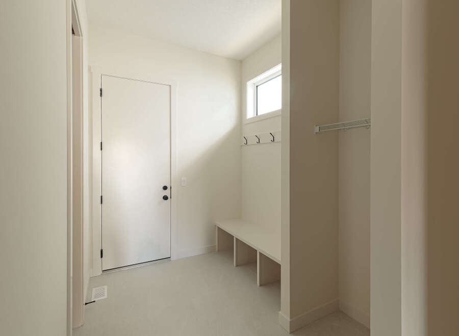 Step into this inviting entryway, featuring a sleek white door with modern black hardware, leading into a bright and airy space.