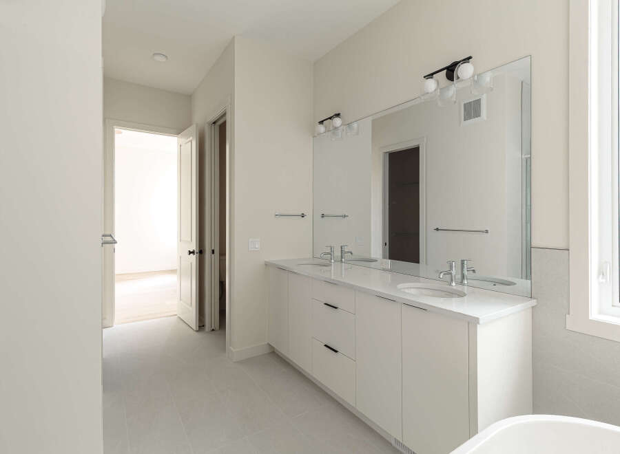 Step into this modern bathroom featuring a sleek double vanity with white quartz countertops and undermount sinks, perfect for a busy household.