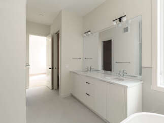Step into this modern bathroom featuring a sleek double vanity with white quartz countertops and undermount sinks, perfect for a busy household.