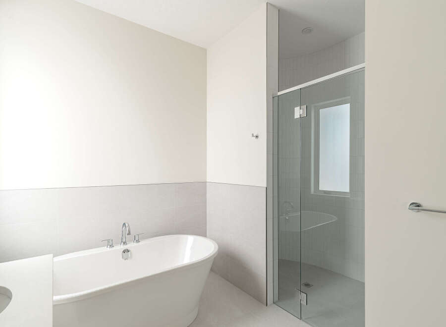 Experience modern luxury in this stunning bathroom, featuring a freestanding soaking tub and a sleek glass-enclosed shower.