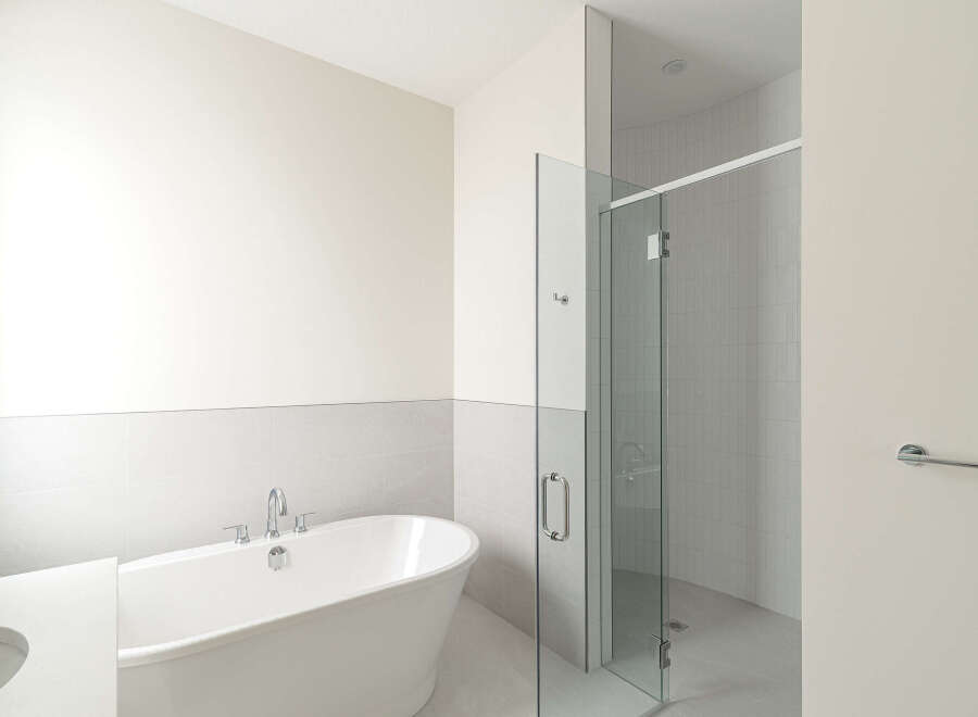Experience modern luxury in this stunning bathroom, featuring a sleek freestanding bathtub and a spacious glass-enclosed shower with elegant tilework.