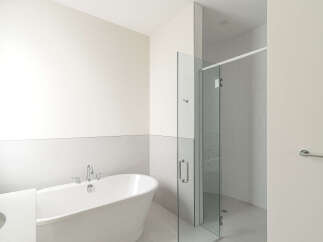 Experience modern luxury in this stunning bathroom, featuring a sleek freestanding bathtub and a spacious glass-enclosed shower with elegant tilework.