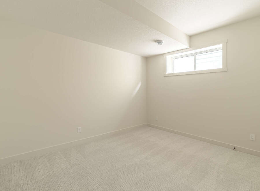 This empty room features a neutral color palette with light beige walls and a textured light gray carpet.