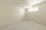 This empty room features a neutral color palette with light beige walls and a textured light gray carpet.