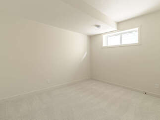 This empty room features a neutral color palette with light beige walls and a textured light gray carpet.