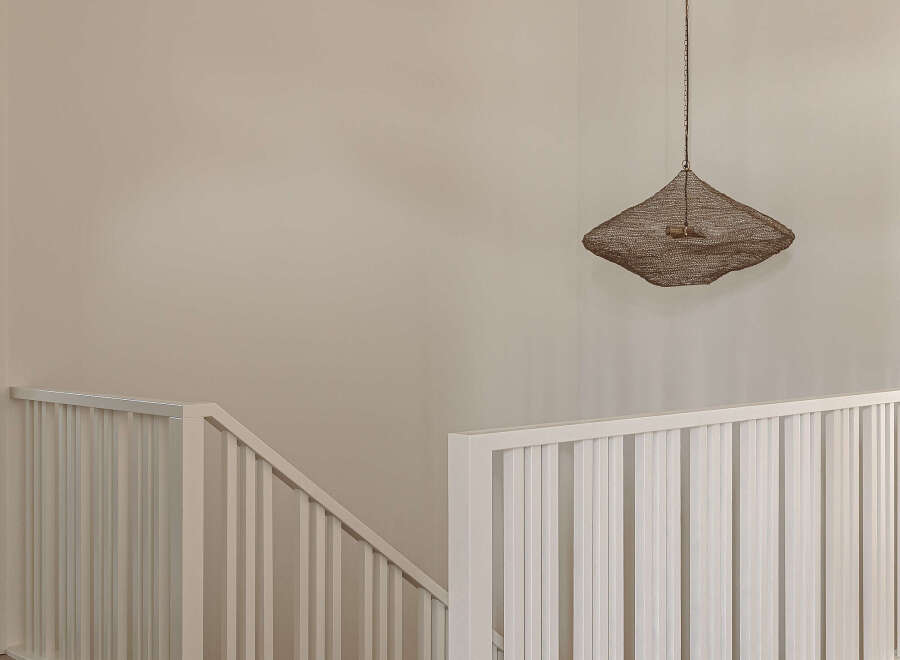 This modern home features a bright and airy staircase with white railings and light wood flooring, creating a seamless flow throughout the space.