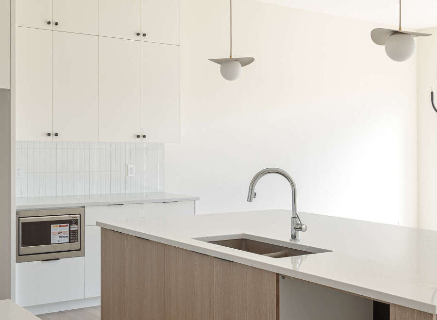 Experience modern living in this stunning kitchen, featuring sleek white cabinetry and a striking wood-grain island.