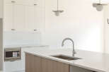 Experience modern living in this stunning kitchen, featuring sleek white cabinetry and a striking wood-grain island.