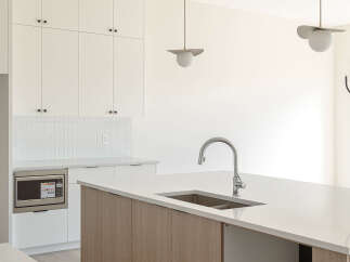 Experience modern living in this stunning kitchen, featuring sleek white cabinetry and a striking wood-grain island.