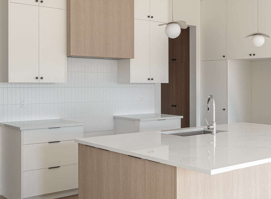 Experience modern luxury in this stunning kitchen, featuring sleek white cabinetry complemented by warm wood accents on the island and range hood.