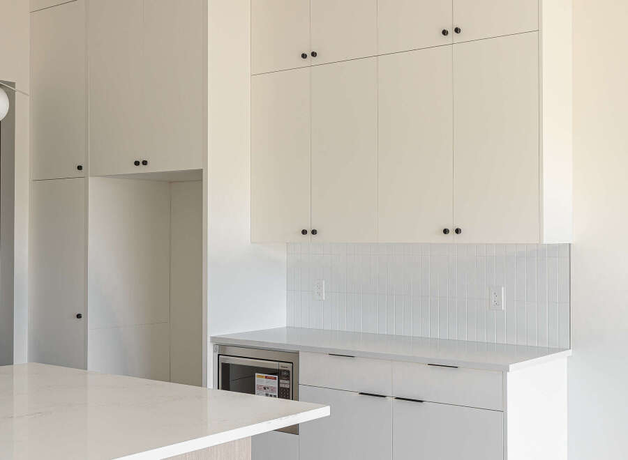 Experience modern living in this stunning kitchen featuring sleek white cabinetry with minimalist black hardware.