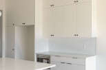 Experience modern living in this stunning kitchen featuring sleek white cabinetry with minimalist black hardware.