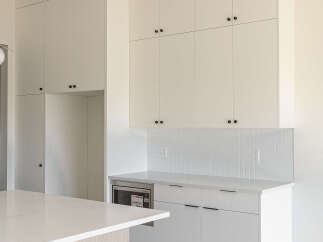 Experience modern living in this stunning kitchen featuring sleek white cabinetry with minimalist black hardware.
