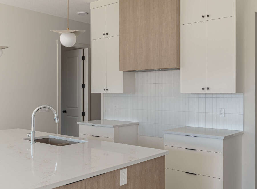 Experience modern living in this stunning kitchen featuring sleek white cabinetry and a beautiful wood-paneled range hood.