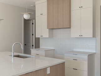 Experience modern living in this stunning kitchen featuring sleek white cabinetry and a beautiful wood-paneled range hood.