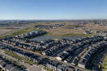 Discover this stunning aerial view of a modern suburban neighborhood, showcasing a collection of contemporary homes with dark roofs and neutral-toned exteriors.