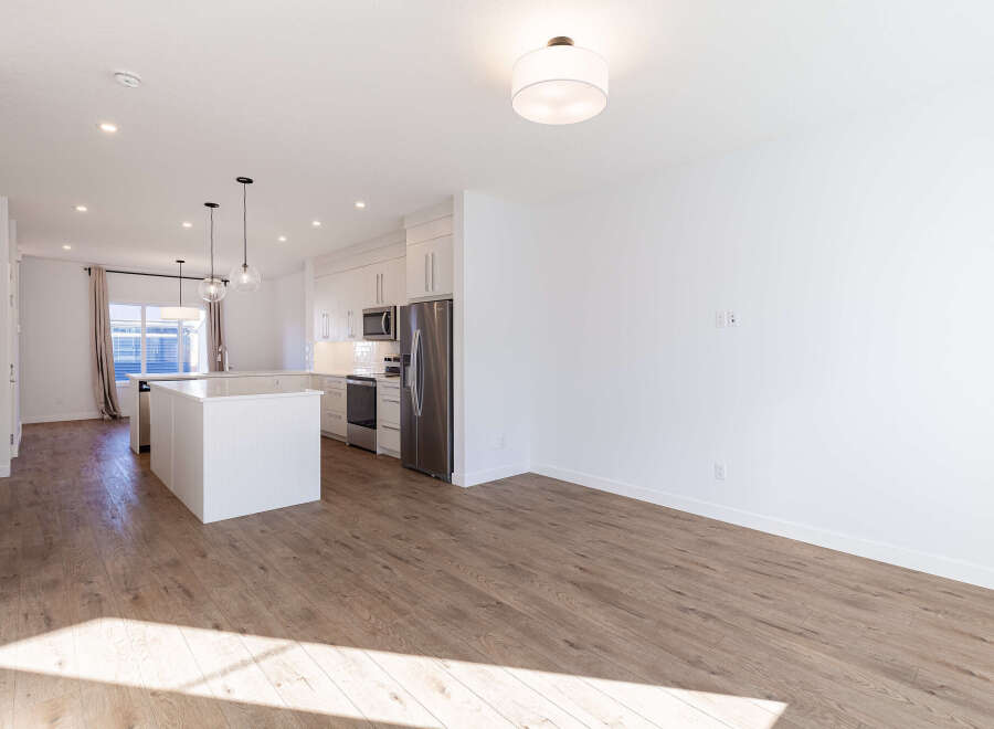 Experience modern living in this stunning open-concept home featuring a sleek white kitchen with stainless steel appliances and a spacious island perfect for entertaining.