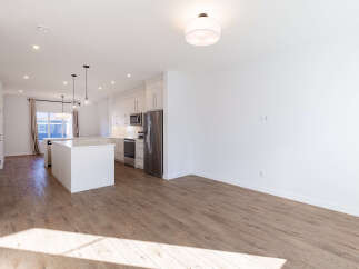 Experience modern living in this stunning open-concept home featuring a sleek white kitchen with stainless steel appliances and a spacious island perfect for entertaining.
