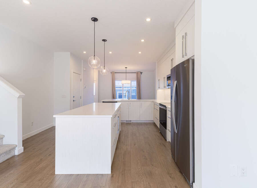 Experience modern living in this stunning kitchen featuring a large white island with ample seating and sleek cabinetry.