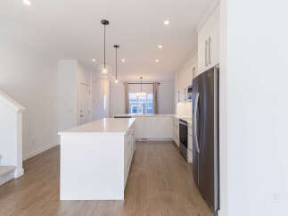 Experience modern living in this stunning kitchen featuring a large white island with ample seating and sleek cabinetry.