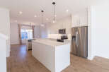 Experience modern living in this stunning kitchen, featuring sleek white cabinetry, a spacious island with a waterfall countertop, and stainless steel appliances.