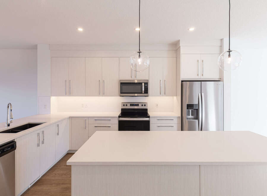 Experience modern living in this stunning kitchen, featuring sleek, light wood cabinetry and a spacious quartz island perfect for entertaining.