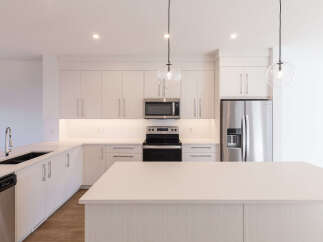 Experience modern living in this stunning kitchen, featuring sleek, light wood cabinetry and a spacious quartz island perfect for entertaining.