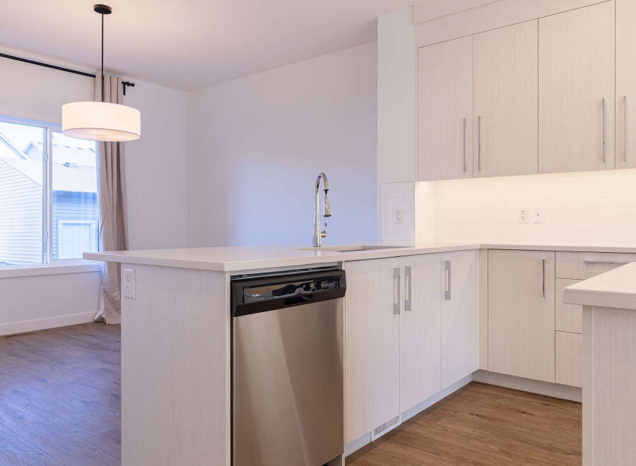 Experience modern living in this stunning kitchen featuring sleek, light wood cabinetry and a spacious island with a built-in dishwasher.