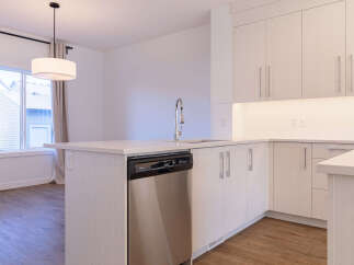 Experience modern living in this stunning kitchen featuring sleek, light wood cabinetry and a spacious island with a built-in dishwasher.