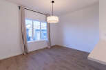 This dining area features a large window with neutral curtains, allowing natural light to flood the space.