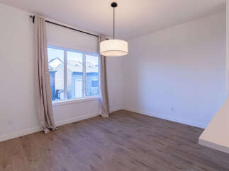 This dining area features a large window with neutral curtains, allowing natural light to flood the space.