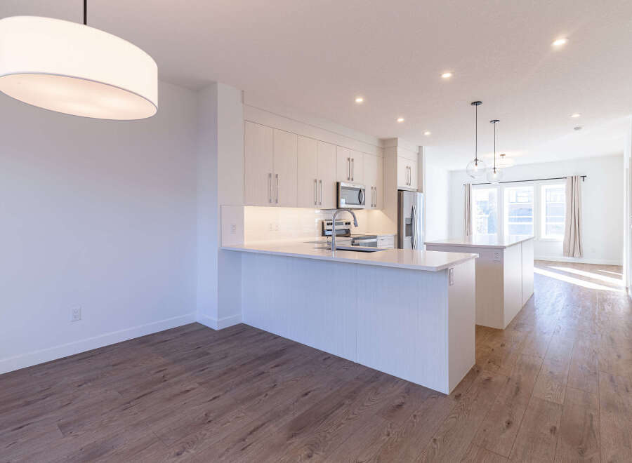 Experience modern living in this stunning kitchen featuring sleek white cabinetry, a spacious island with a waterfall countertop, and a subway tile backsplash.
